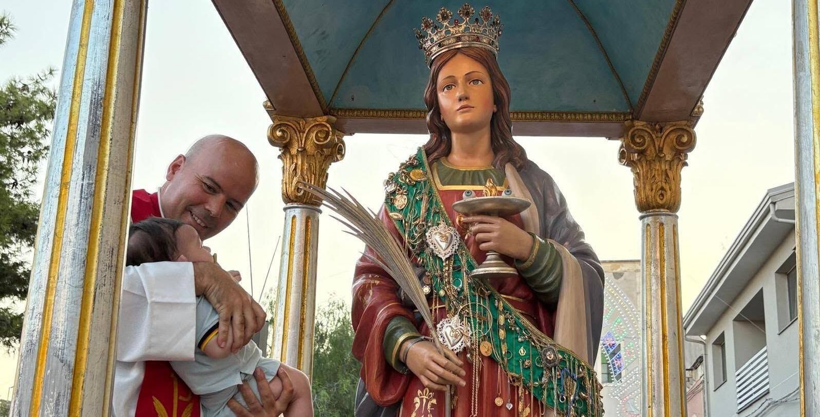 Gerardo Bouzada sostiene a un bebé durante la procesión de Santa Lucía en Picanello (Catania).