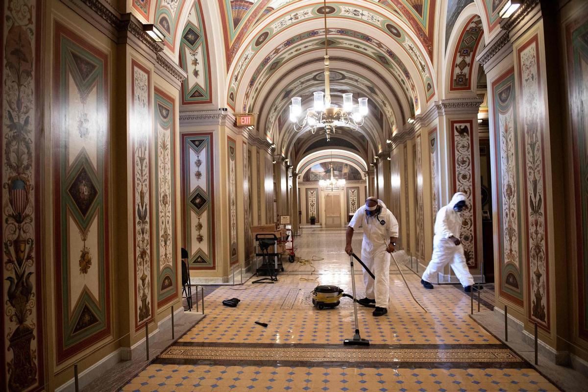 Workers clean damage near an overrun Capitol Police checkpoint a day after a pro-Trump mob broke into the US Capitol January 7, 2021, in Washington, DC. (Photo by Brendan Smialowski / AFP)