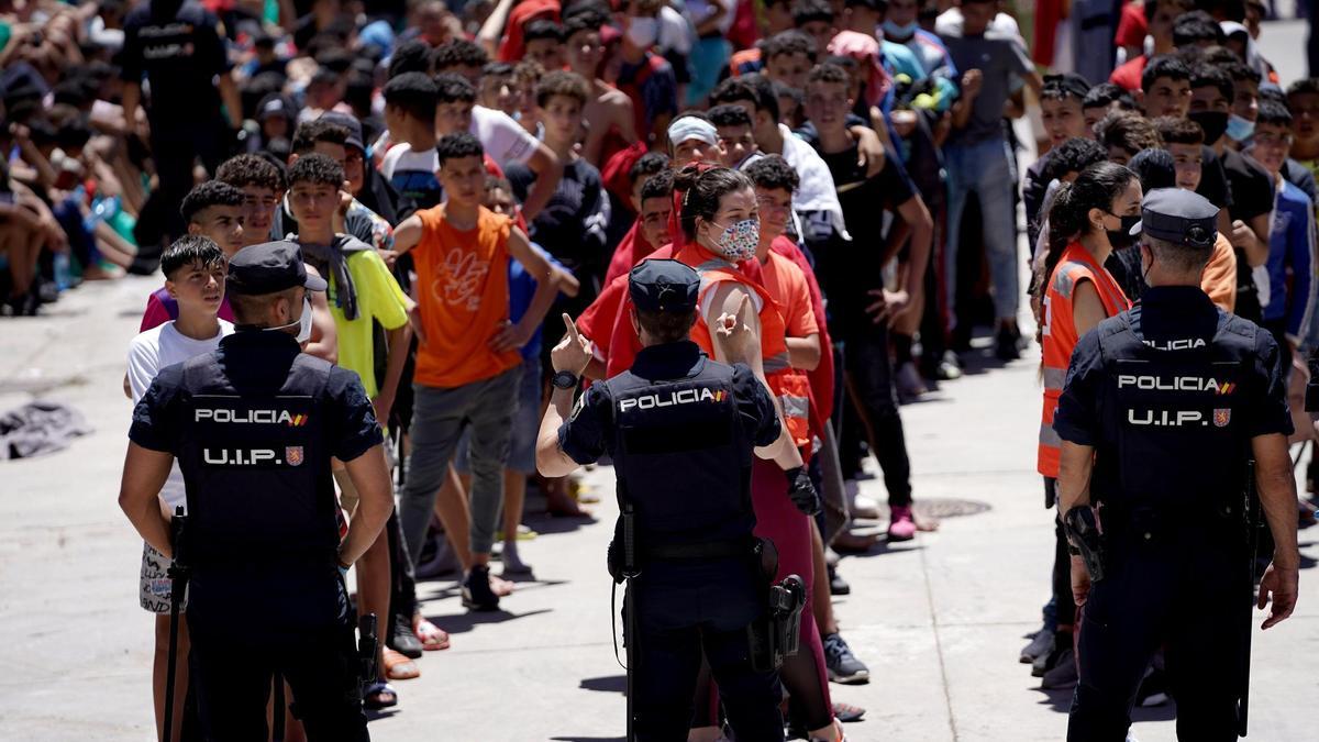 &lt;p&gt;Policías ante menores marroquís alineados en las naves de El Tarajal, Ceuta. Mayo de 2021&lt;/p&gt;