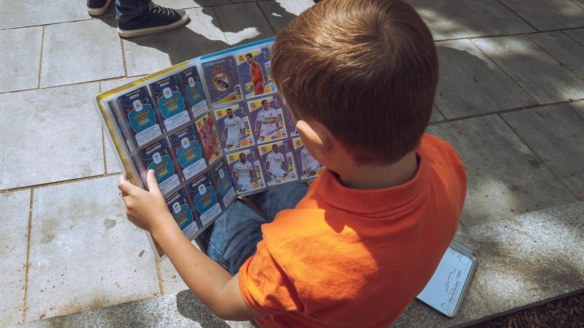 Un niño mira su álbum de cromos.