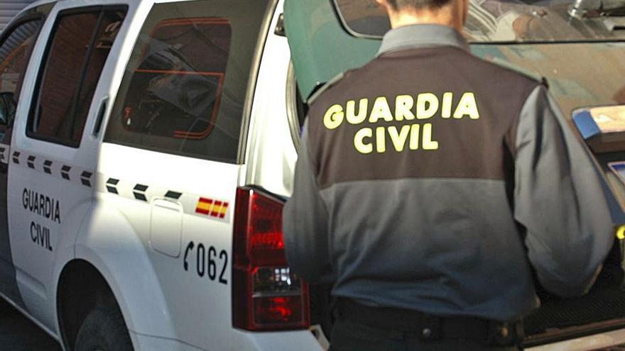 Un agente de la Guardia Civil junto al coche oficial.