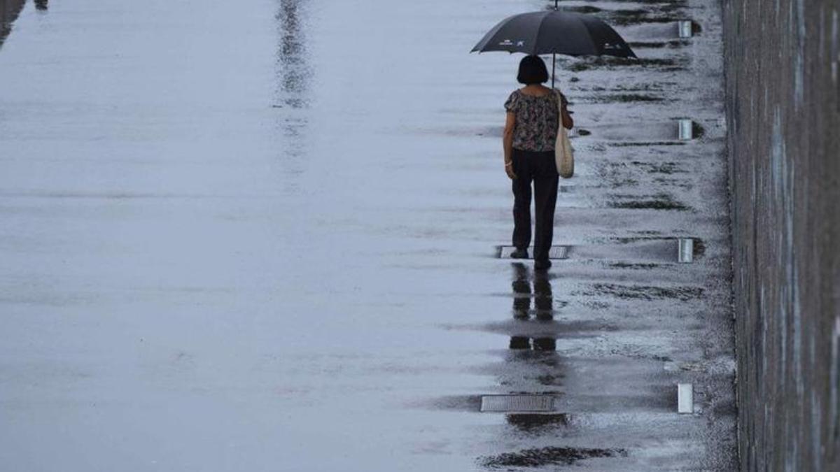 Una mujer se protege de la lluvia con un paraguas.