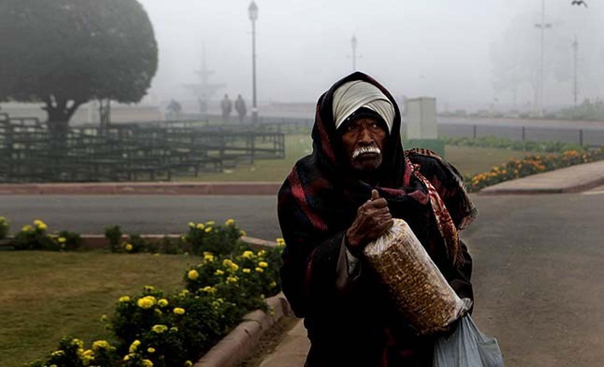 Un home gran es dirigeix a la feina enmig de la boira i en un matí fred a Nova Delhi (Índia).