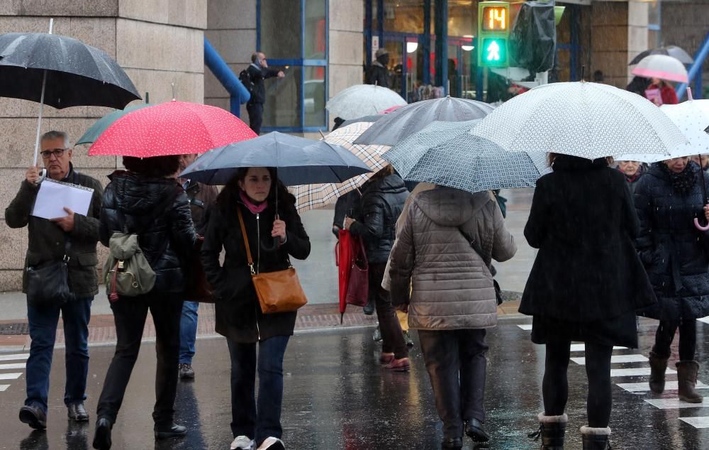 Viandantes tratan de protegerse de la lluvia, en el centro de Vigo