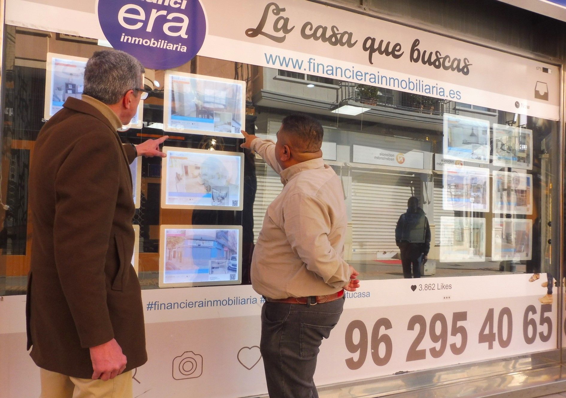 Dos personas observan el escaparate de una agencia inmobiliaria en Gandia.