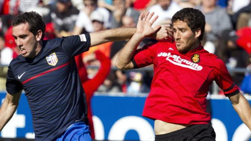 El defensa del Atlético de Madrid Diego Godín (i) pugna por el balón con el delantero israelí del RCD Mallorca Tomer Hemed.