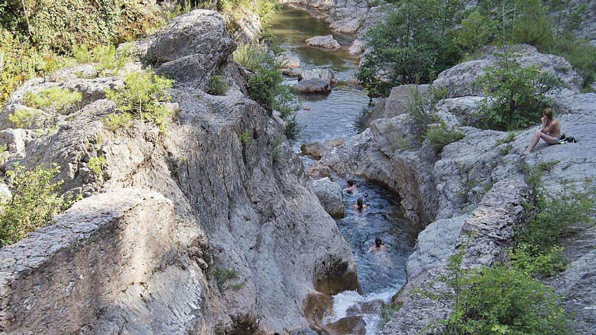 Uns banyistes gaudint de la frescor d’una de les gorgues d’Albanyà.