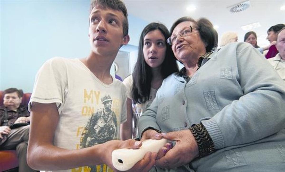 Alumnos del colegio Sagrada Familia de Tortosa instruyen a una residente del Sant Miquel Arcàngel.