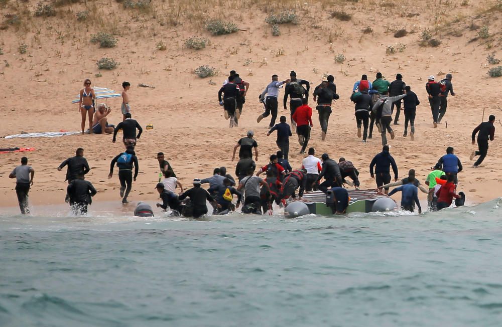 Una patera llega a una playa de Cádiz ante la mirada de los bañistas