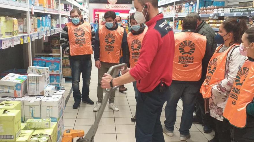 Miembros de Unións Agrarias en la retirada de leche de lineales en dos supermercados de Santiago.