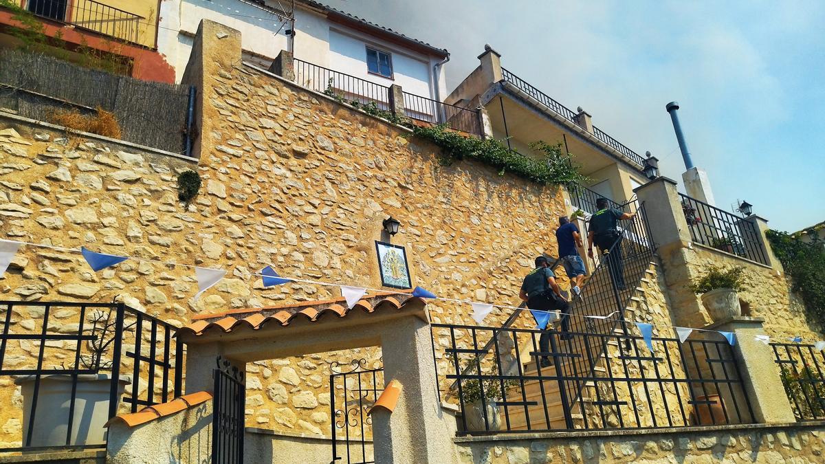 Agentes de la Guardia Civil suben a una de las casas para avisar a sus residentes de que tienen que desalojar el pueblo