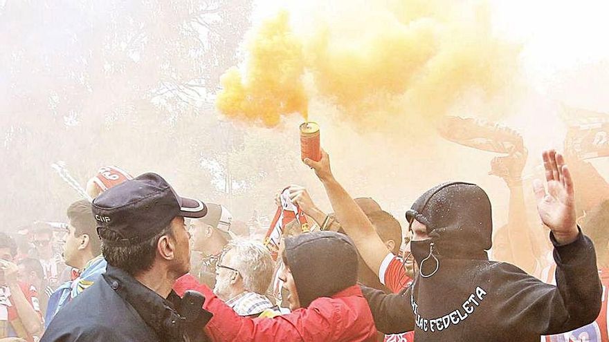 Un agente, tratando de frenar a varios seguidores del Sporting durante los disturbios en la avenida del Molinón en septiembre de 2017.