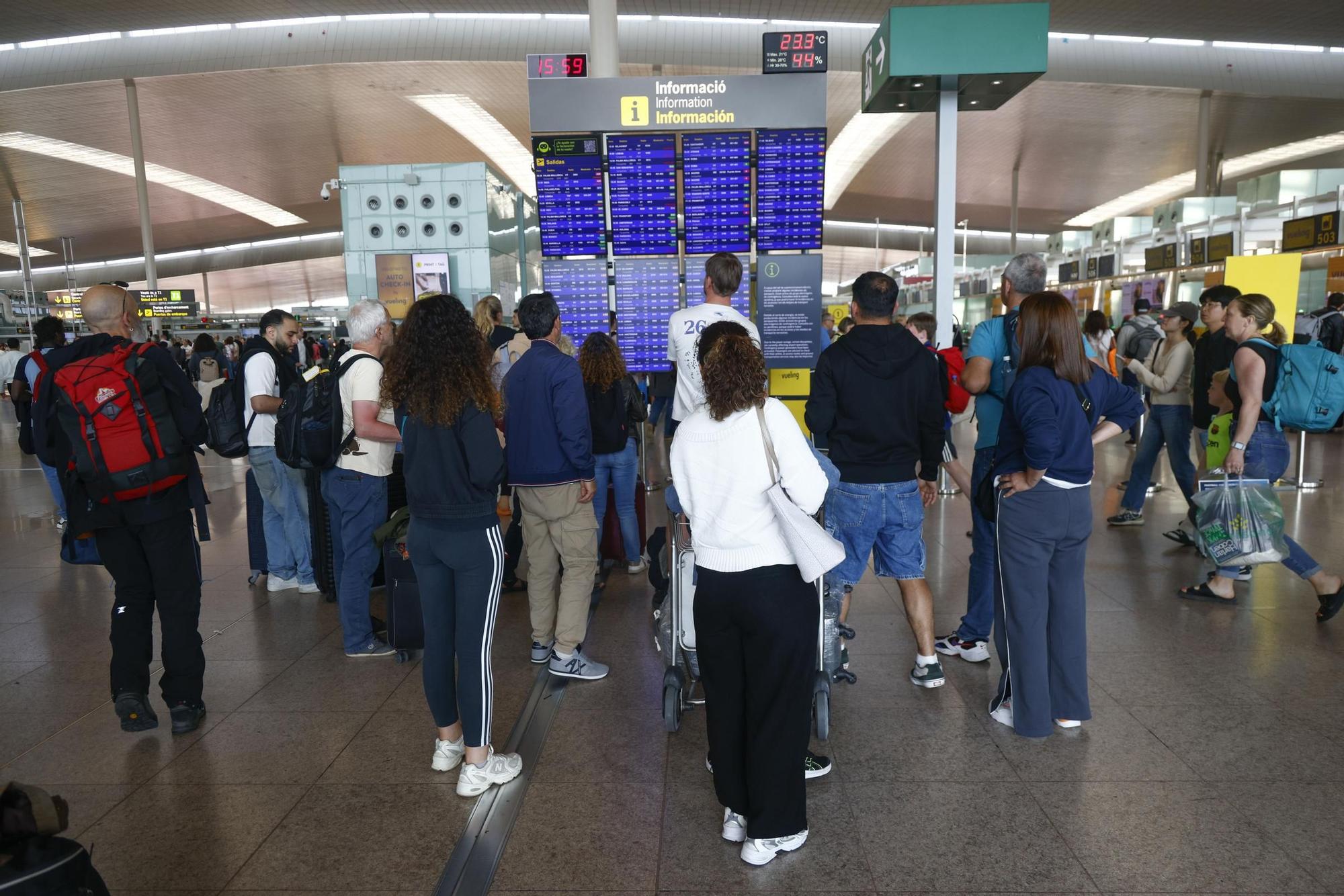 Pasajeros atentos a las pantallas del aeropuerto de Barcelona durante el apagón de este lunes.