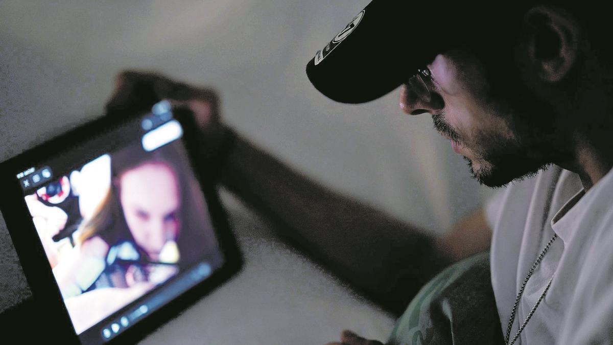 Un joven ve contenido pornográfico en un dispositivo, escondido en su habitación.