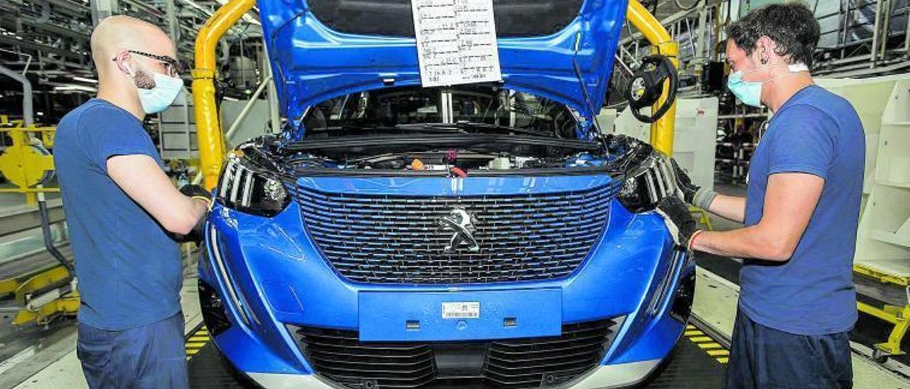 Dos trabajadores de la factoría de Vigo del Grupo PSA, en la línea de montaje del nuevo Peugeot 2008 (proyecto V20-P24).