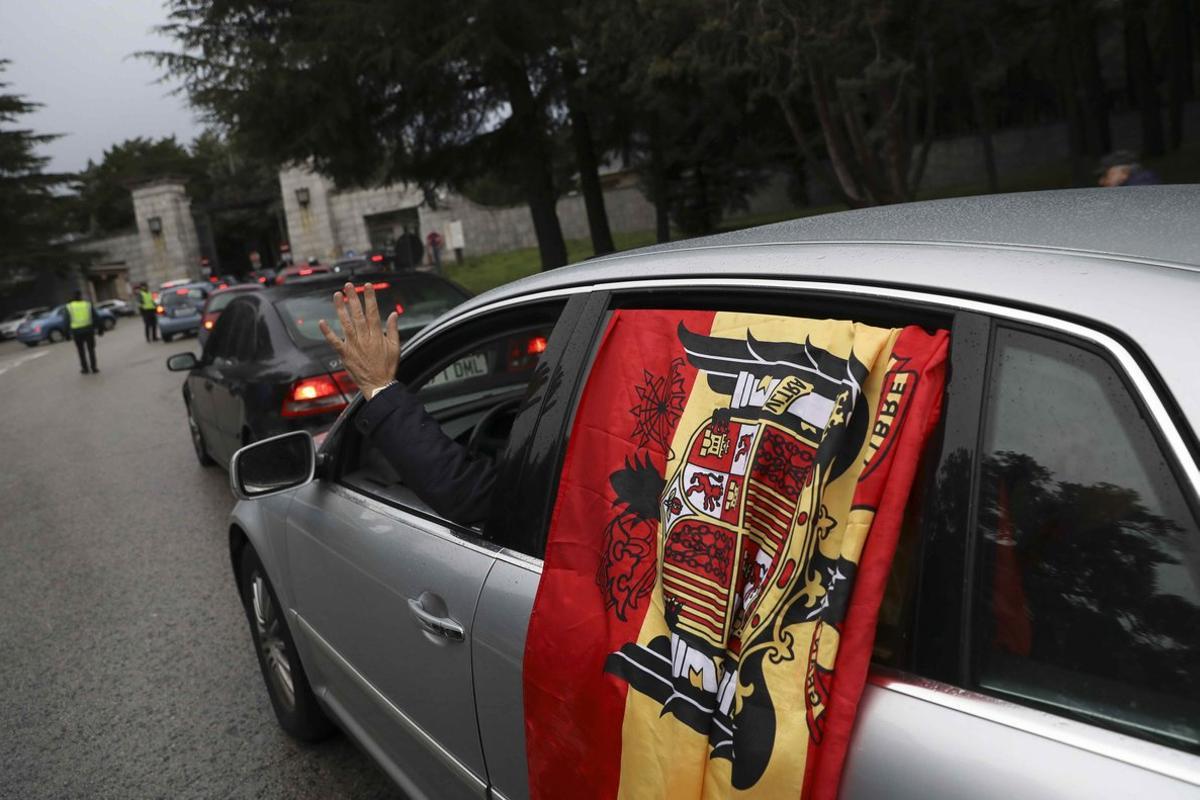 A passenger waves from a car displaying a pre-constitutional Spanish flag as it enters the  Valle de los Caidos (The Valley of the Fallen), the mausoleum holding the remains of Spanish dictator Francisco Franco, in San Lorenzo de El Escorial, outside Madrid, Spain, November 20, 2018. REUTERS/Susana Vera