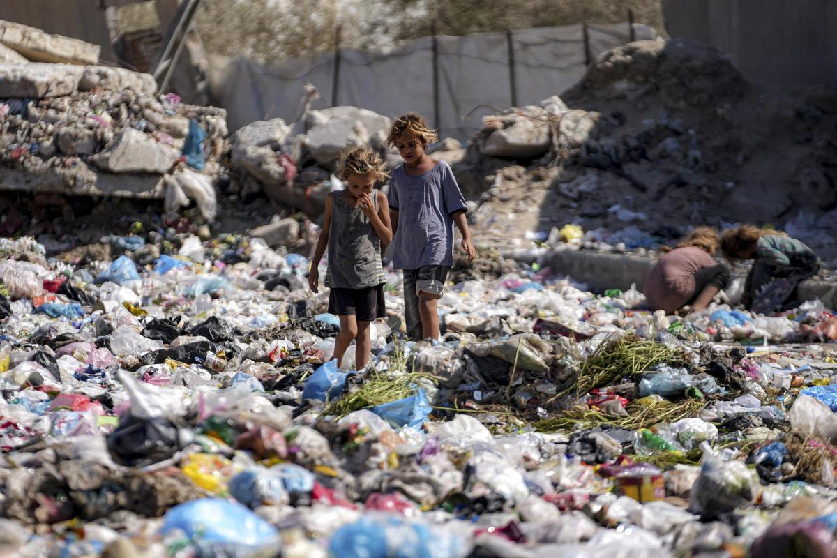 Niños desplazados revisan la basura en una calle de Deir al-Balah, en el centro de la Franja de Gaza, el jueves 29 de agosto de 2024.