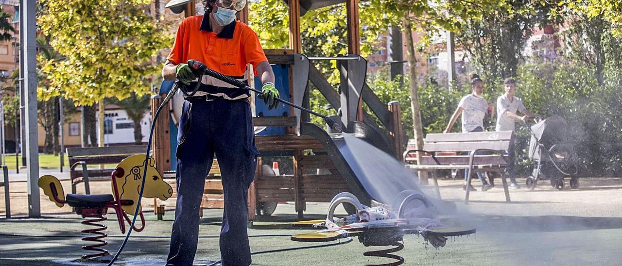 Un operario de la UTE limpia un parque infantil en Alicante.