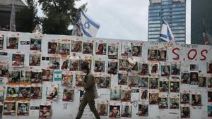 Una soldado pasa junto a un mural con los rostros y los nombres de los secuestrados por Hamás, en la llamada Plaza de los Rehenes de Tel Aviv