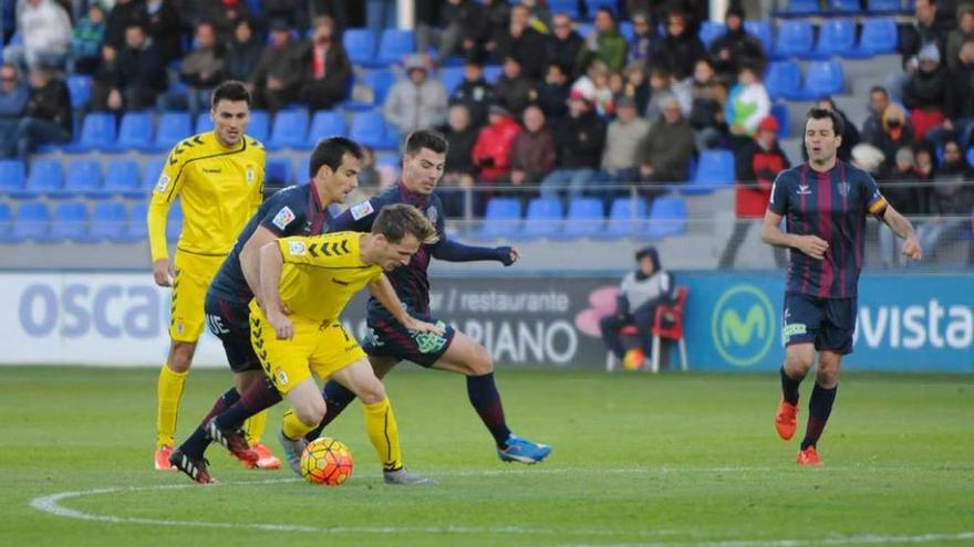 Susaeta, autor del gol del Oviedo, sale trastabillado en el centro del campo entre dos jugadores del Huesca, con Vila siguiendo la jugada.