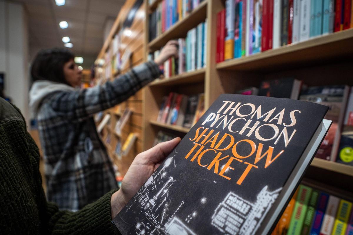 Dos jóvenes, en la estantería de novelas en inglés de un comercio de Barcelona.