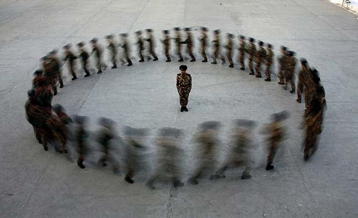 Un comandant observa com els reclutes de la policia paramilitar corren en un cercle durant un entrenament en una base militar a Hami (Xina).