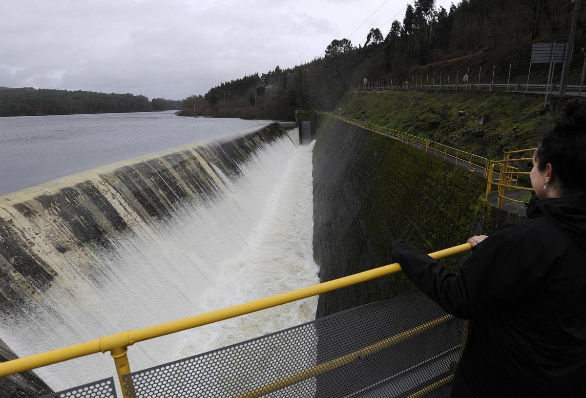 Una joven observa el aliviadero de Portodemouros en pleno funcionamiento.