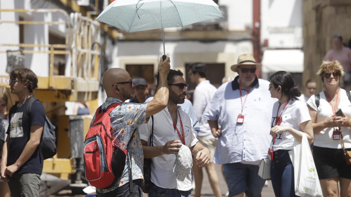 Turistas se protegen del sol en el centro de Córdoba.