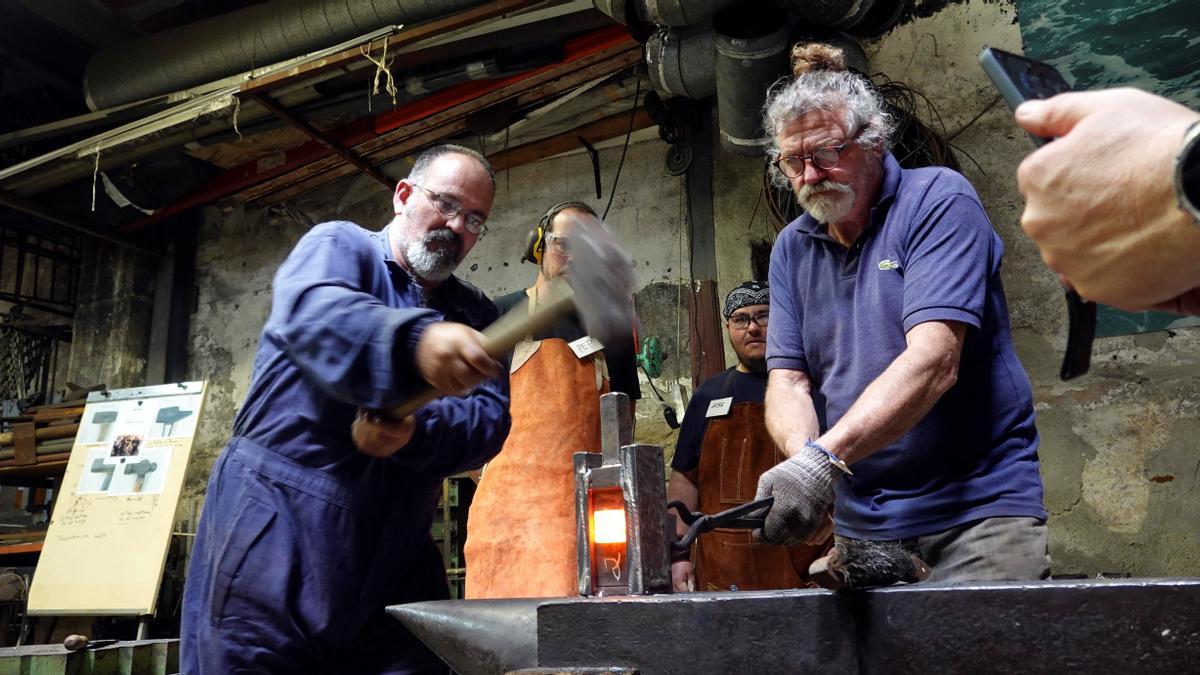 El maestro israelí Boaz Yakin (derecha) enseña a hacer un martillo, este lunes, en el taller de forja del Raval.