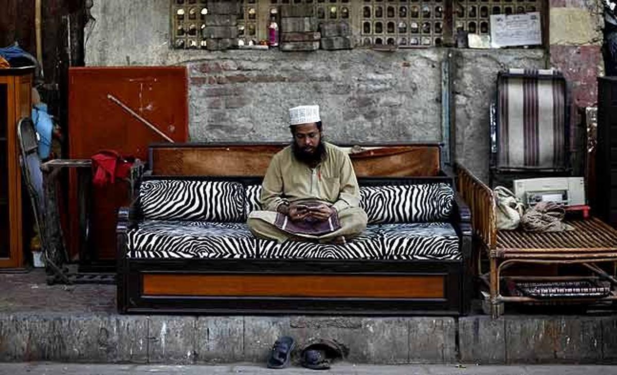 Noor Mohammed, un comerciant de 53 anys d’edat, llegeix l’Alcorà fora de la seva botiga de mobles a Mumbai (Índia).