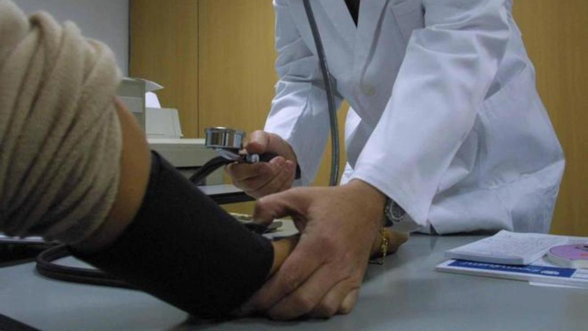 Un médico mide la tensión a un paciente.