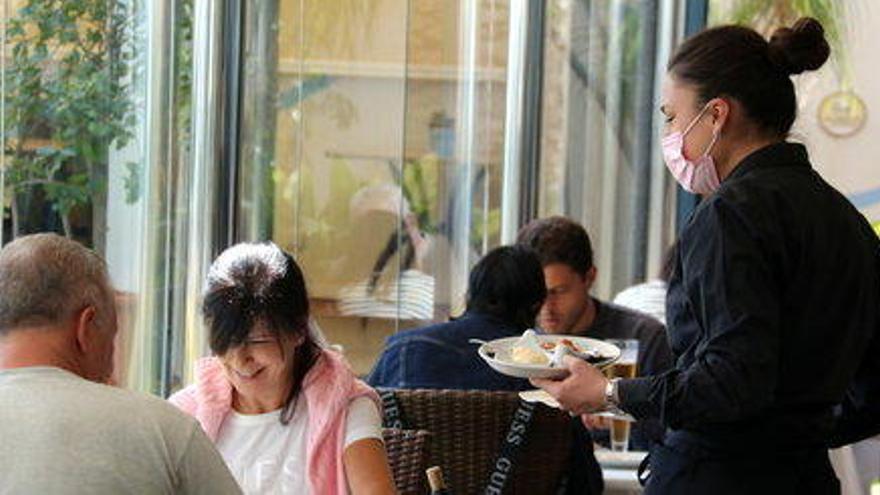 Una cambrera servint plats a dos clients al restaurant de l&#039;Hotel Miami de Sant Carles de la Ràpita