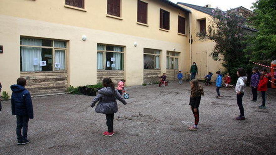 Pla general del pati de l&#039;escola Jordi Pere Cerdà de Sallagosa, situada a la banda administrativament francesa de la Cerdanya, on es veuen alumnes més grans esperant en punts distanciats i els petits jugant al darrere.