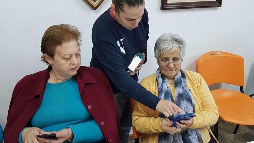 Dos mujeres aprenden a manejar el teléfono móvil bajo las instrucciones de Jennifer Rodríguez.