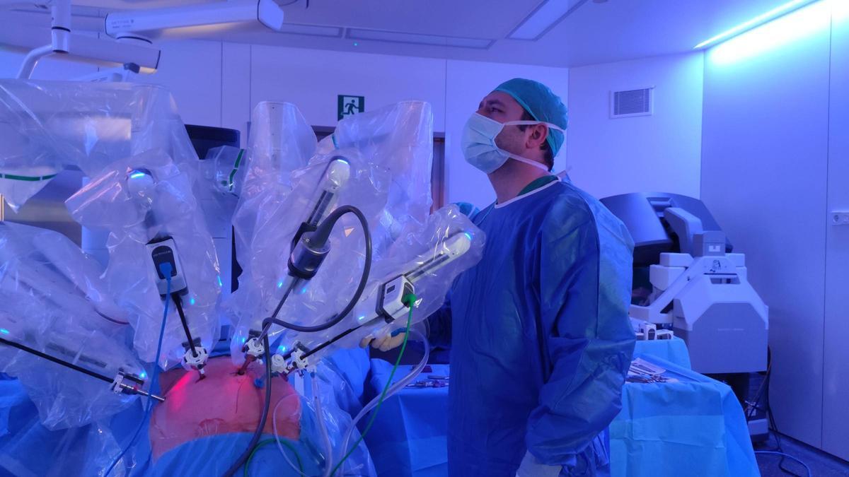 Els braços articulats del robot sobre el pacient, i al costat, el cirurgià auxiliar