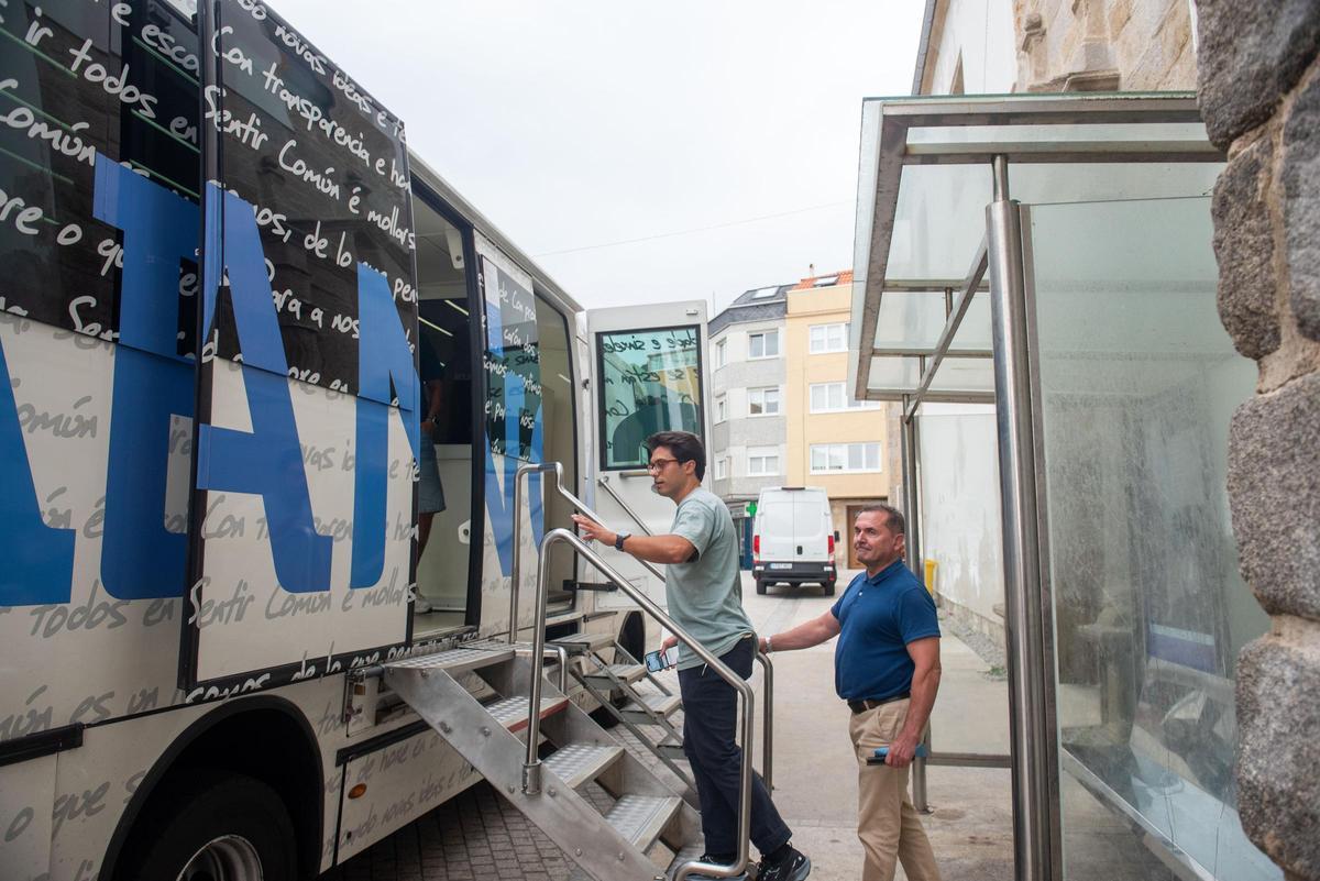 Dos usuarios entran en el bus itinerante de Abanca en Caión.