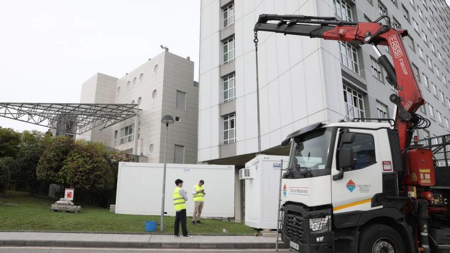 Operarios instalando ayer las casetas de obra, junto al Hospital de Cabueñes. | Juan Plaza