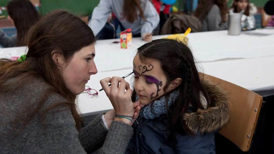 Arriba, compradores en los puestos de la Jornada Solidaria Familiar, ayer. Abajo, una niña en el pintacaras del evento.