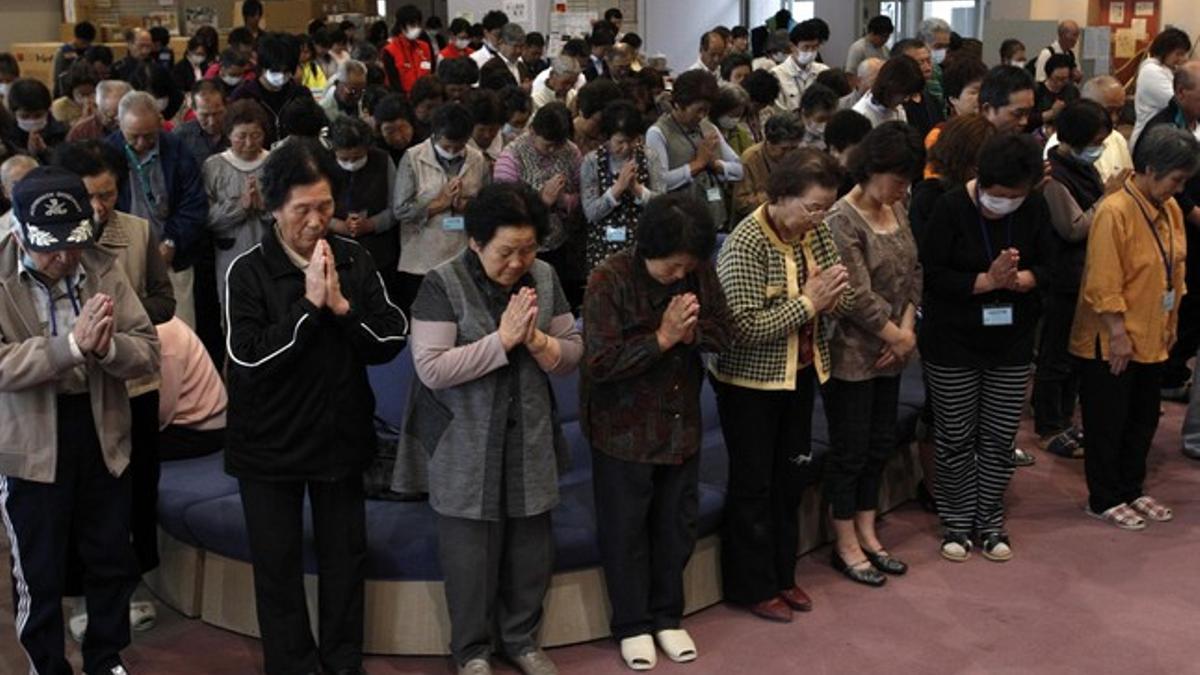 Evacuados de la prefectura de Fukushima guardan un minuto de silencio por las víctimas del terrremoto.