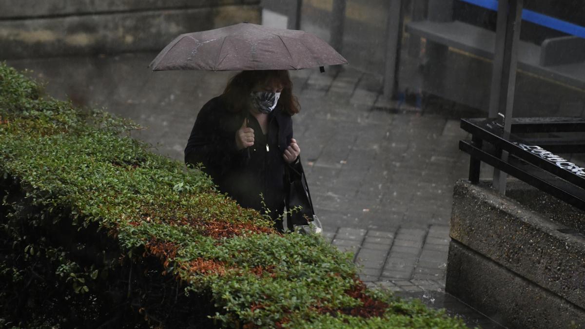 Una persona camina bajo la lluvia protegida con un paraguas, en Madrid.