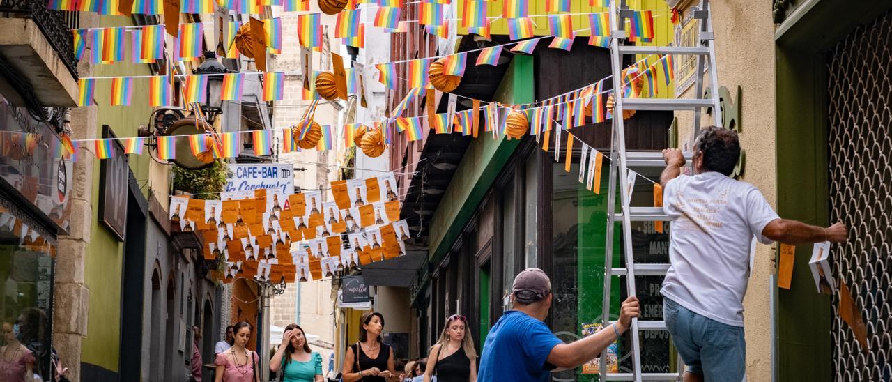 Los trabajadores colocan las banderolas y los farolillos por las calles del centro