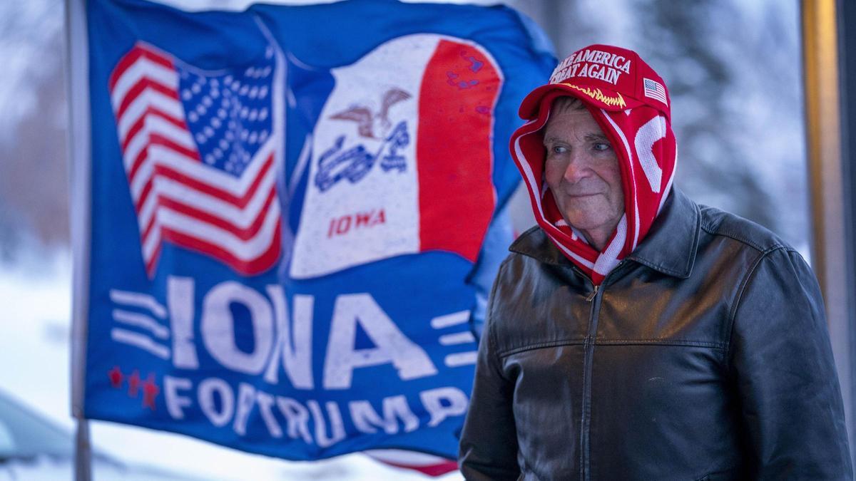 Un hombre camina junto a una bandera de apoyo para el candidato Trump en Iowa