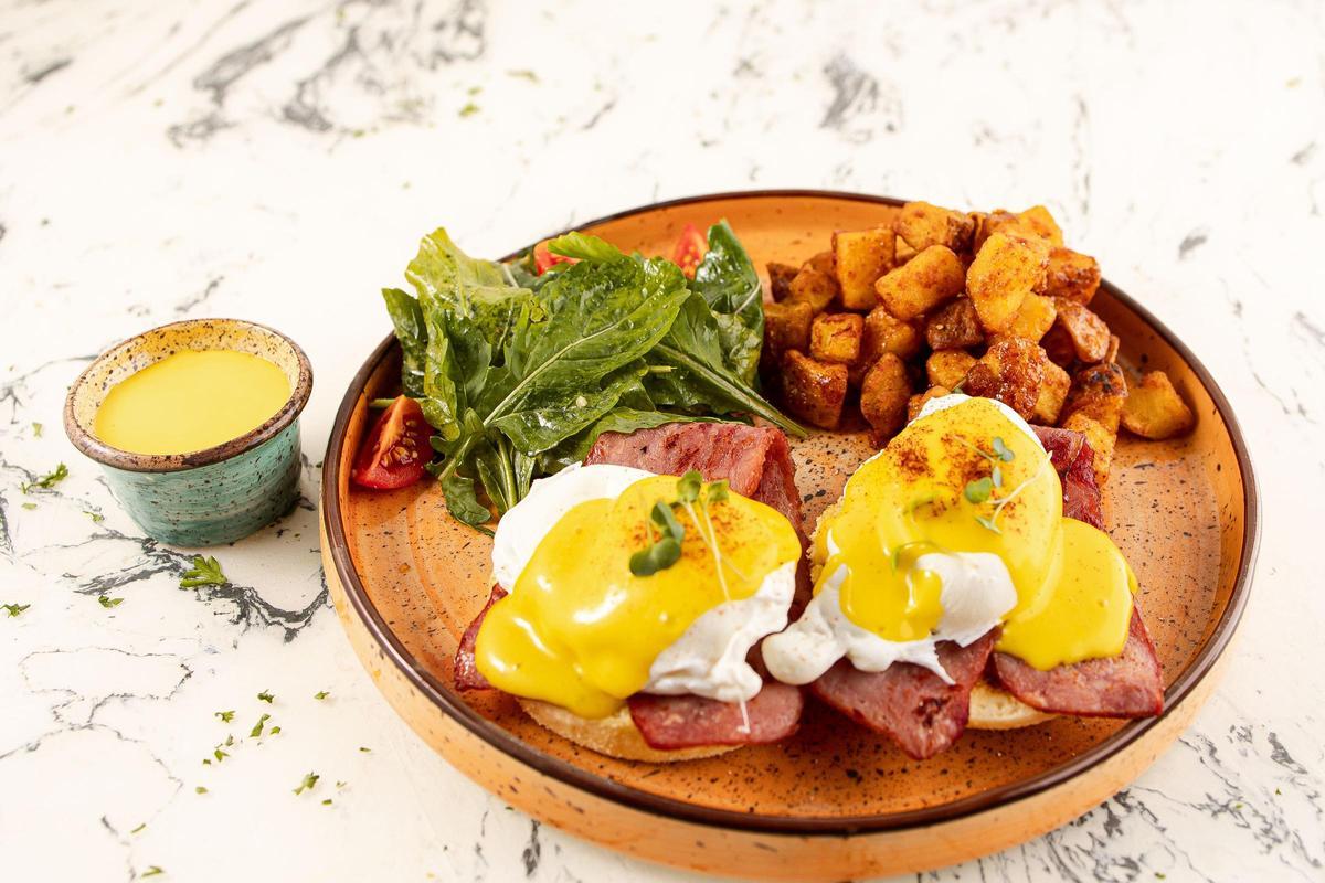 Huevos escalfados sobre pan tostado, cubiertos de una generosa salsa holandesa y acompañados habitualmente de bacon o salmón