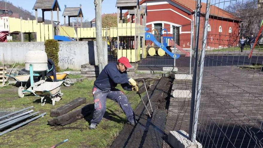 Las obras de mejora del parque de Pola de Laviana, con un trabajador quitando traviesas de madera.