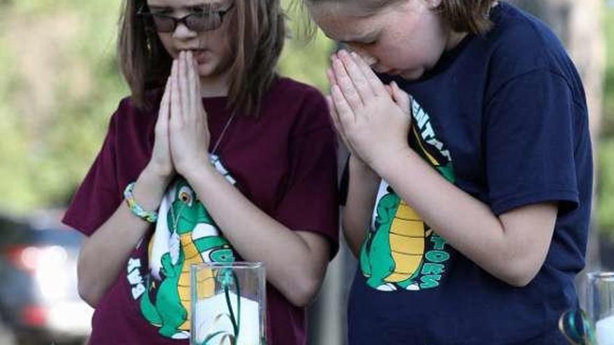 Dos niñas rezan durante un homenaje en Santa Fe.