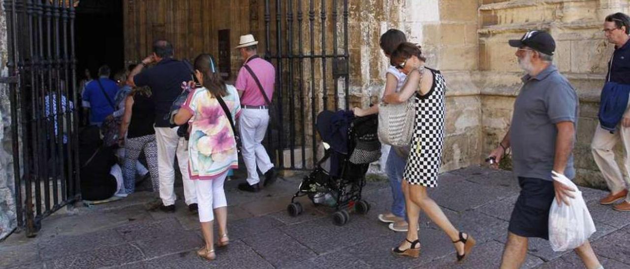 Varios turistas entran en la Catedral por la puerta principal del templo.