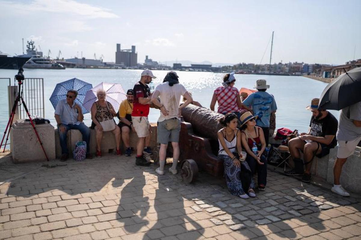 Visitantes y aficionados a la observación astronómica esperan en el Port de la Maria, en Tarragona, para contemplar el eclipse total de Sol.