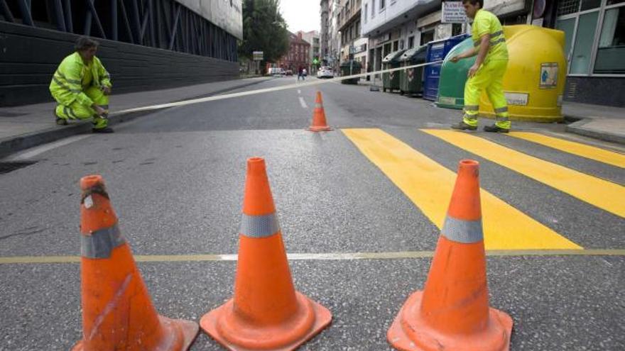 Dos operarios preparan un paso de peatones provisional próximo al centro de salud de Llano Ponte.