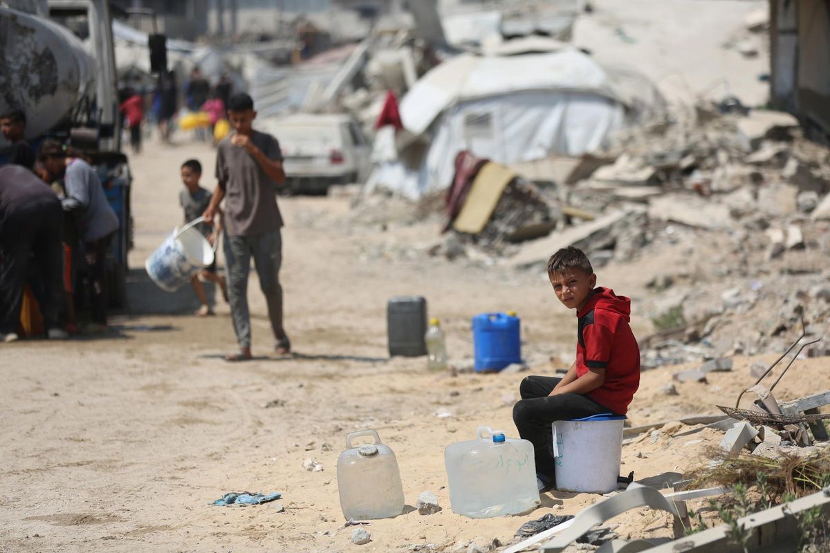 Archivo - Arxiu - Xiquets palestins esperen per a intentar arreplegar aigua davant de l'ofensiva d'Israel contra la Franja de Gaza i les seues restriccions al lliurament d'ajuda humanitària (arxiu)