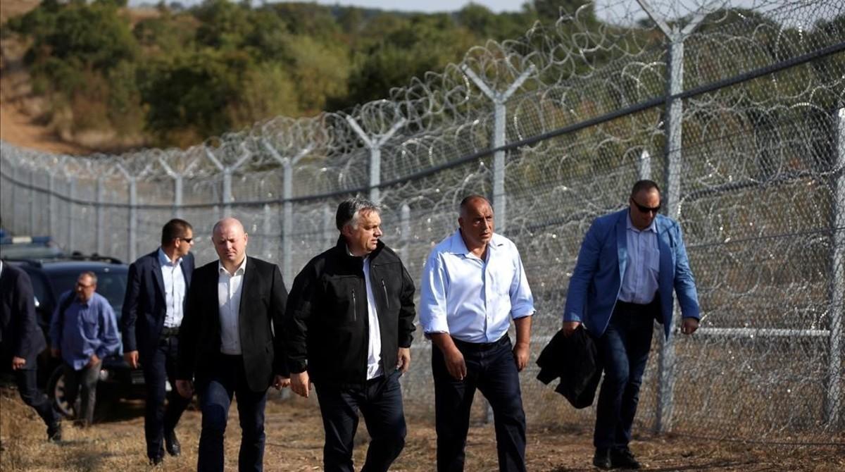 El primer ministro húngaro, Viktor Orbán (centro, con chaqueta negra) y su homólogo búlgaro, Boiko Borisov (derecha) inspeccionan la valla de alambradas construida en la frontera con Turquía, cerca de Lesovo (Bulgaria), el 14 de septiembre del 2016.